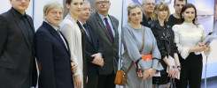 Grupa osób pozuje do zdjęcia. Wśród nich mężczyźni i kobiety w strojach formalnych i casualowych.