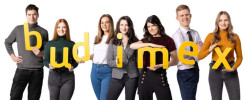 Siedem osób trzyma żółte litery tworzące napis "budimex".