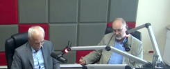 Dwóch mężczyzn w studiu radiowym przy mikrofonach. Mężczyźni siedzą przy stole, rozmawiają.