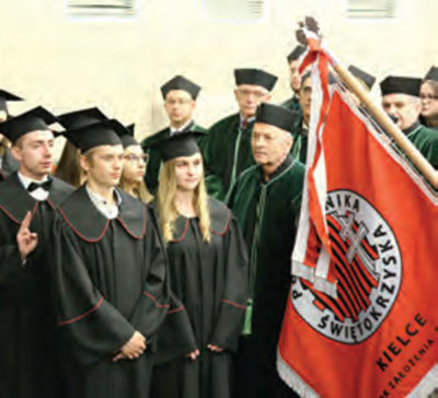 Uroczystość akademicka z udziałem studentów w togach i biretach. Widoczna jest czerwona flaga z napisem "Kielce".