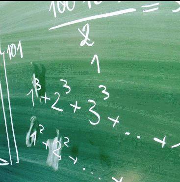 Zielona tablica z równaniami matematycznymi. Widoczne liczby, potęgi i symbole.