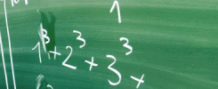 Zielona tablica z zapisanymi wzorami matematycznymi, w tym potęgami i ułamkami. Widoczne liczby i symbole matematyczne.